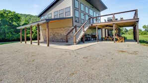 Et moderne hus med to etager, en overdækket terrasse, en stensokkel og en trappe til øverste etage.