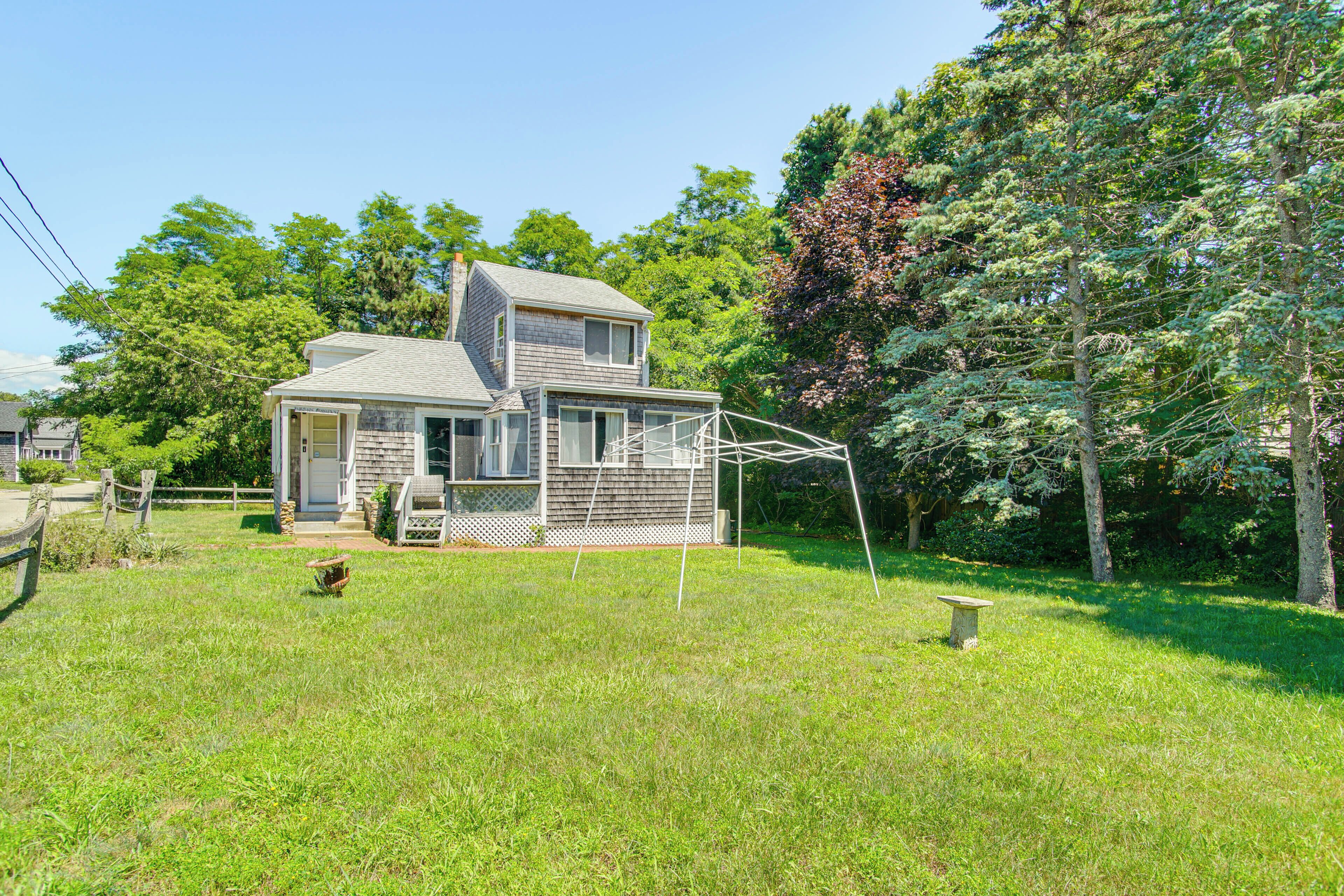 A two-story house with a porch, surrounded by a grassy yard and trees.
