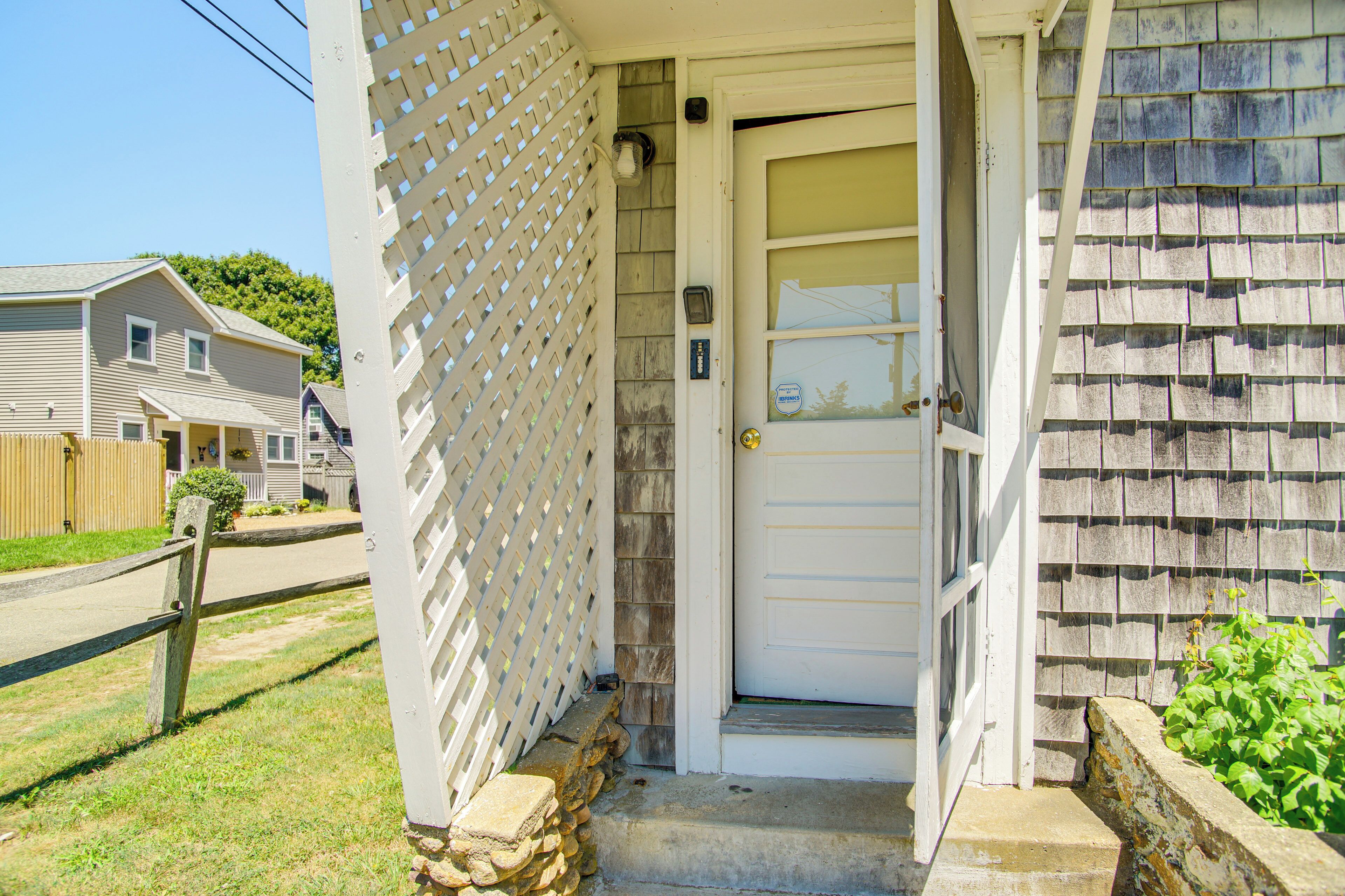 A house with a white door, a wooden fence, and a stone wall.