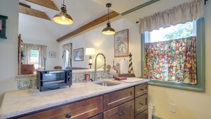 A kitchen with a built-in toaster, a sink, wooden cabinets, and a window with floral curtains.