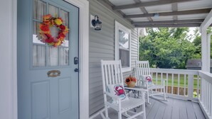 A porch with a light blue door, white rocking chairs, and a wreath.