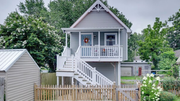 A two-story house with a balcony, a front porch, and a wooden fence.