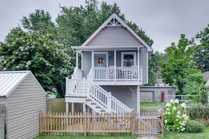 A two-story house with a balcony, a front porch, and a wooden fence.