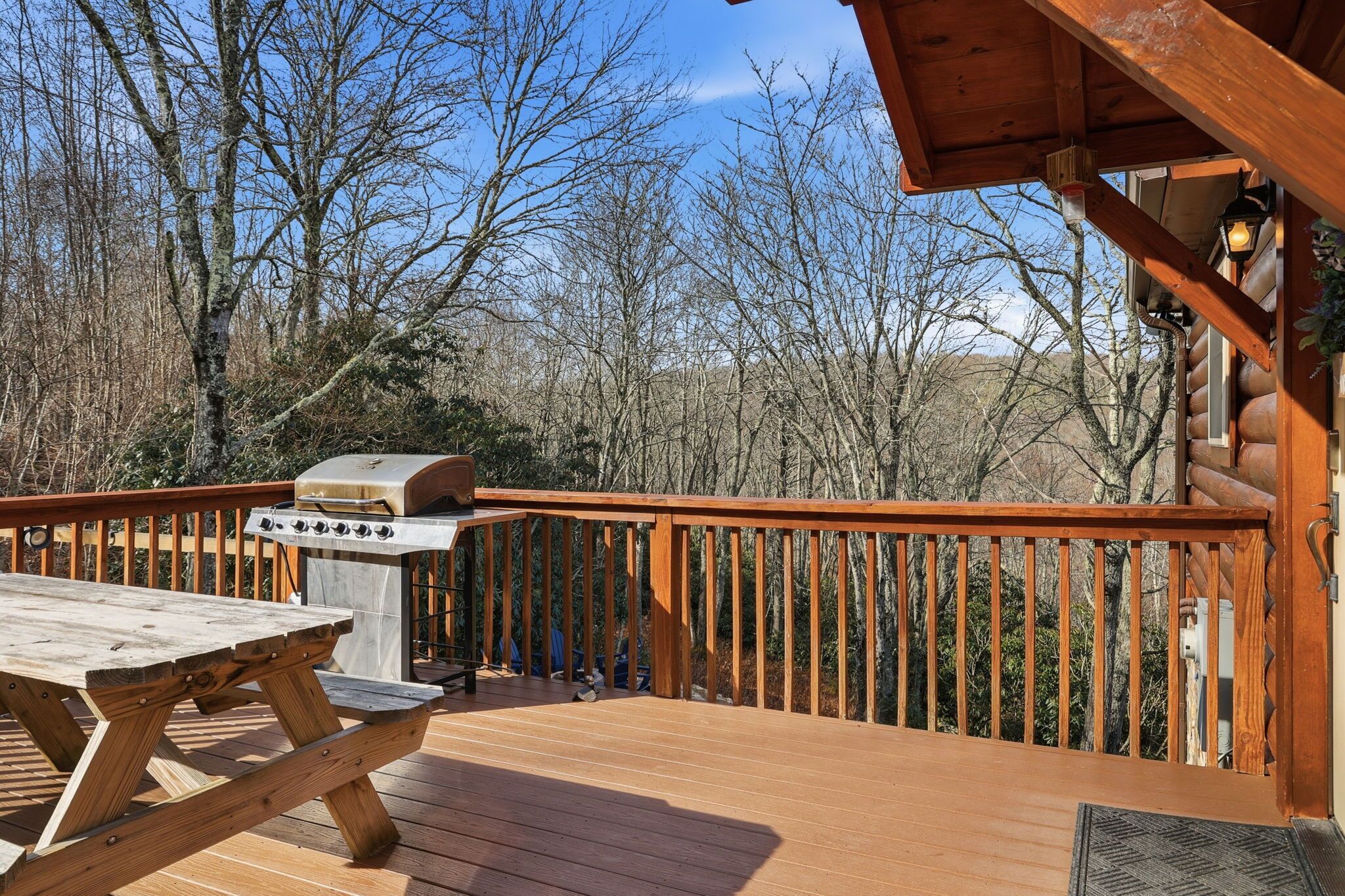 A wooden deck with a barbecue grill and picnic table.