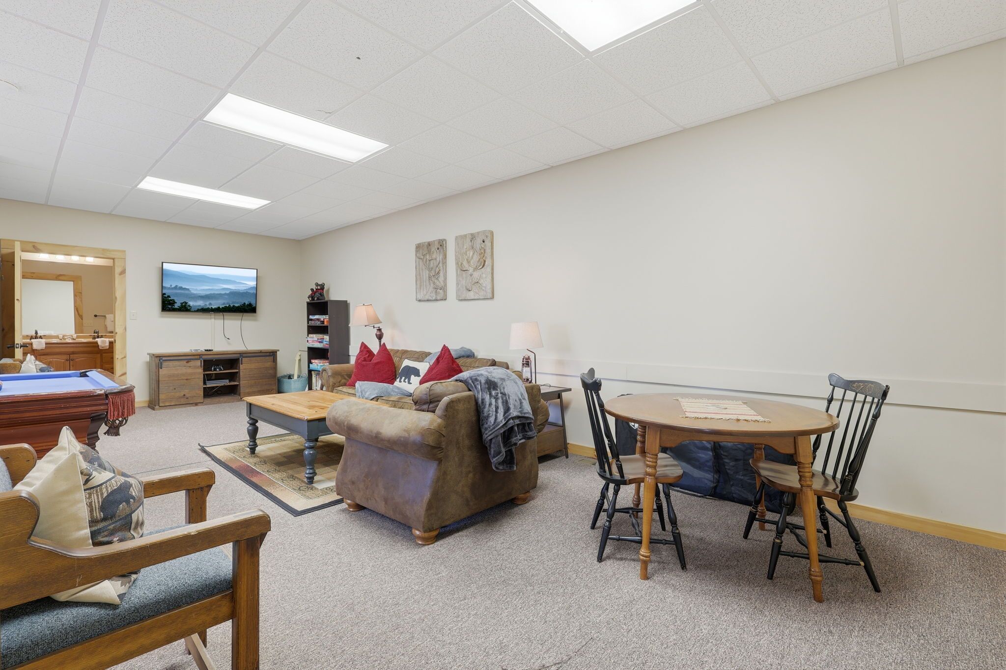 A living room with a pool table, a sofa, a coffee table, and a dining table with chairs.