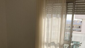 A hotel room with a bed, a small table with towels, a sliding glass door to an outdoor area with a chair, and a tiled floor. - B Beach Apartment Armaçao de Pêra - Apartamento com vista ao mar (Armação de Pêra)