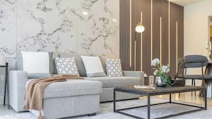 A modern living room with a grey sofa, patterned cushions, a coffee table, and a decorative vase.