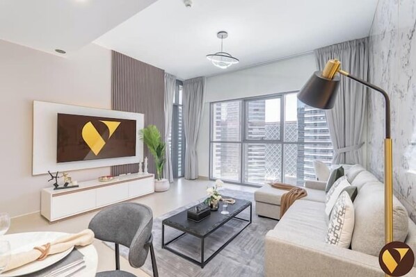 A modern living room with a large flat-screen TV, a sofa, a coffee table, and a floor lamp.