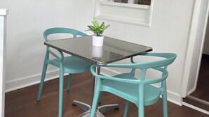 Un comedor con una mesa y dos sillas, una cita enmarcada en la pared y una ventana que da a la cocina.