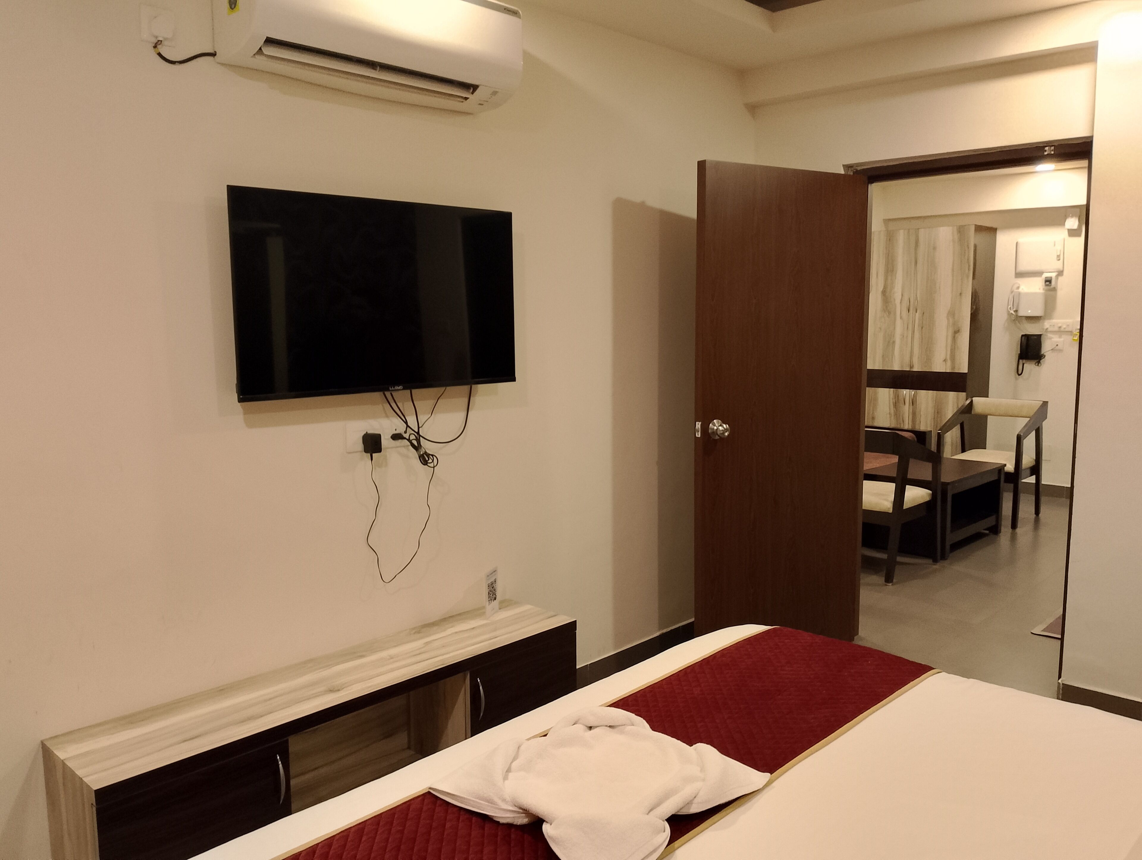Een hotelkamer met een bed, een aan de muur bevestigde televisie, een houten garderobe en een deur naar een badkamer.