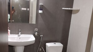 A bathroom with a sink, toilet, and a small trash bin. - Relax, Refresh, Rejoice–Stay at Ananya Palm Beach Apartmentt (Sipasurubili)