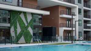 Ein modernes, mehrgeschossiges Gebäude mit einem Schwimmbecken im Vordergrund.