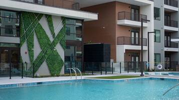 Un immeuble moderne à plusieurs étages, avec une piscine en premier plan.