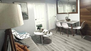 A modern living room with a sofa, a dining table with chairs, a lamp, and a mirror. - Cozy 2-bedroom condo with AC, fitness room in lovely Iloilo City (Iloilo City)