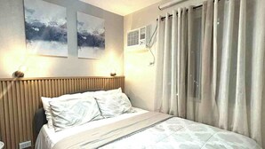 A bedroom with a bed, two wall-mounted air conditioning units, and a window with curtains. - Cozy 2-bedroom condo with AC, fitness room in lovely Iloilo City (Iloilo City)