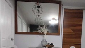 Et moderne spiseområde med et hvidt bord, grå stole og et stort spejl over.