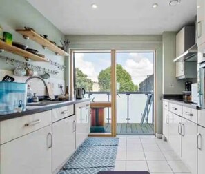 Una cocina moderna con armarios blancos, un amplio ventanal y vistas al exterior.