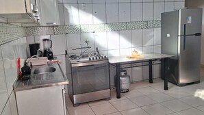 Una cuina moderna amb fogó a gas, nevera, vàter i un cilindre de gas.