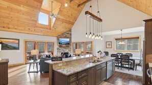 A spacious kitchen with a large island, wooden ceiling, and a stone fireplace. - Last Minute Deals! ~Fire Pit, Hot Tub,  on Creek! (Vilas)