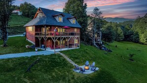 A log cabin with a balcony, outdoor seating, and a fire pit. - Last Minute Deals! ~Fire Pit, Hot Tub,  on Creek! (Vilas)