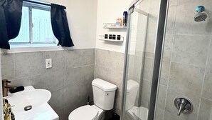 Un baño con inodoro, lavabo y ducha.
