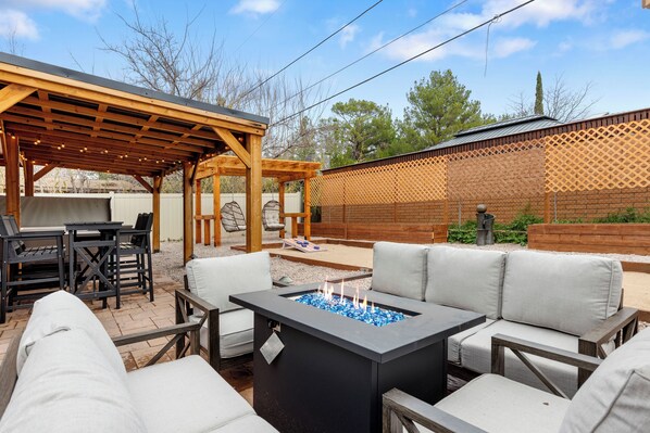 Une terrasse extérieure dotée d’un foyer, de sièges et d’une pergola.
