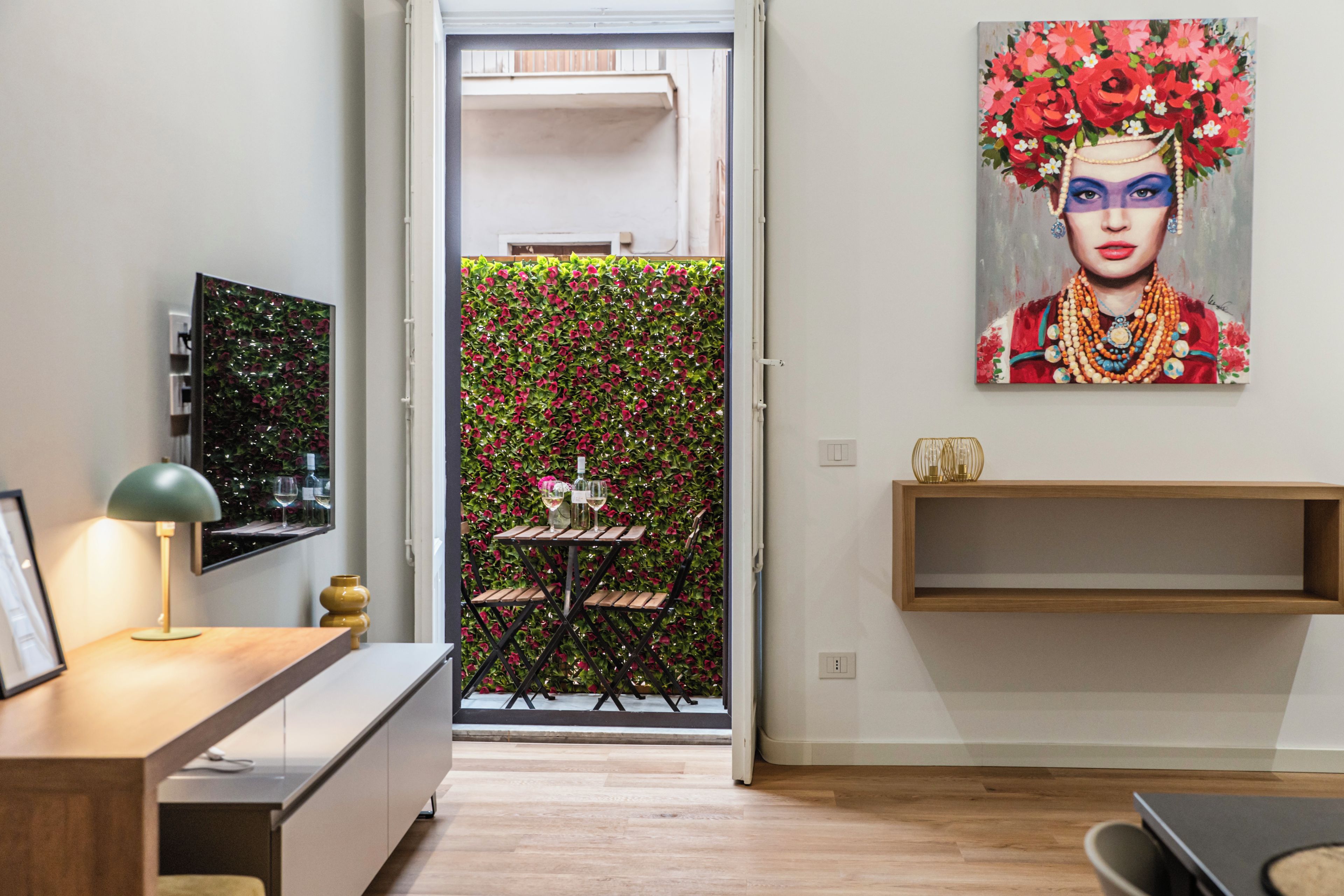 Un intérieur moderne avec un coin repas, un tableau et une vue à travers une porte vitrée.