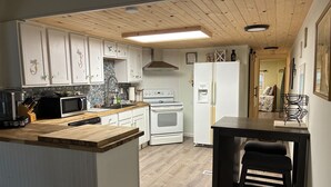 Eine Küche mit weißen Schränken, einer Holz Arbeitsplatte, einem Herd, einer Mikrowelle und einem Kühlschrank.