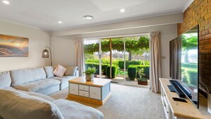 A modern living room with a sofa, coffee table, and TV. - Monkey Gully Retreat - Pool - Mansfield - Sleeps 9 (Mansfield)