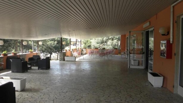 An outdoor patio area with tiled flooring, outdoor seating, and a ceiling with a ribbed design. - PARK HOTEL (Lido di Camaiore)