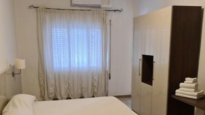 A hotel room with a bed, a wardrobe, a desk with a lamp, and a window with curtains. - PARK HOTEL (Lido di Camaiore)