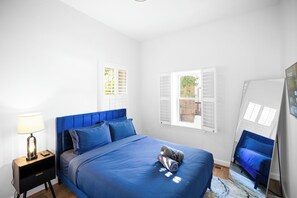 A bedroom with a bed, a nightstand, a lamp, and a window with shutters. - Striking 2bed, 2 Bath B&B in  Washington (Washington)