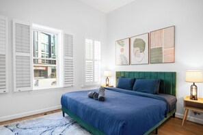A bedroom with a bed, two bedside tables, a green upholstered headboard, and artwork on the wall. - Striking 2bed, 2 Bath B&B in  Washington (Washington)