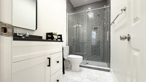 Une salle de bain moderne avec un meuble-lavabo blanc, une cabine de douche en verre et un sol carrelé avec des motifs hexagonaux.