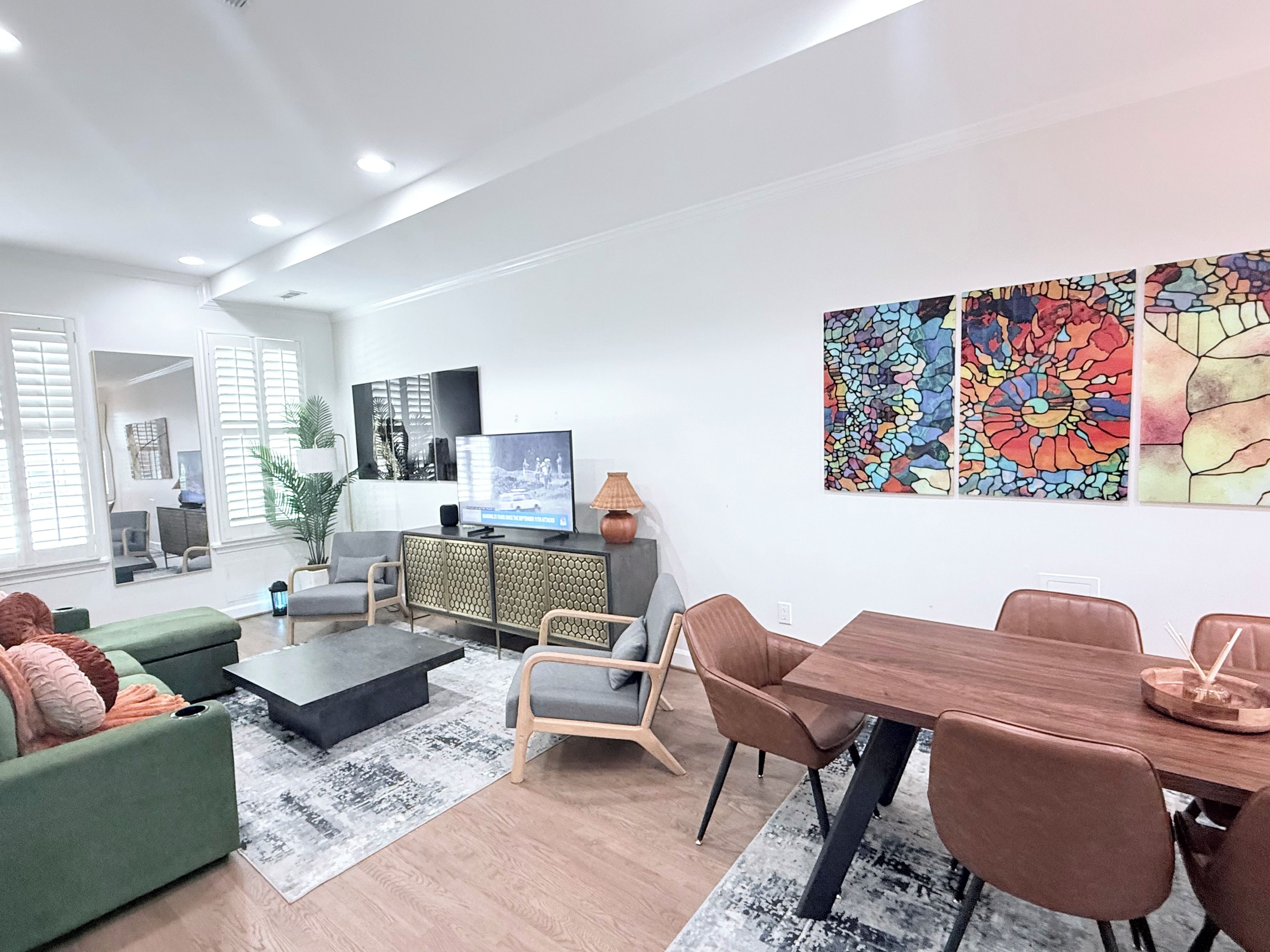 A modern living room with a flat-screen TV, a dining table, and a large window.