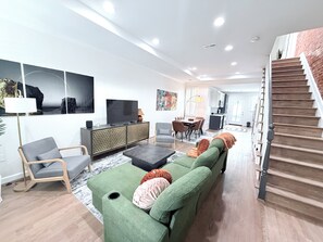 A modern living room with a sofa, chairs, a TV, and a staircase. - Striking 2bed, 2 Bath B&B in  Washington (Washington)