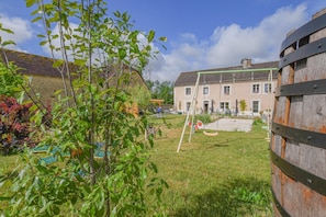 Un quartier résidentiel avec une maison, une balançoire et un tonneau en bois.