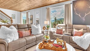 Una sala de estar moderna con sofás de cuero, una mesa de centro con objetos decorativos y grandes ventanales con vistas panorámicas.