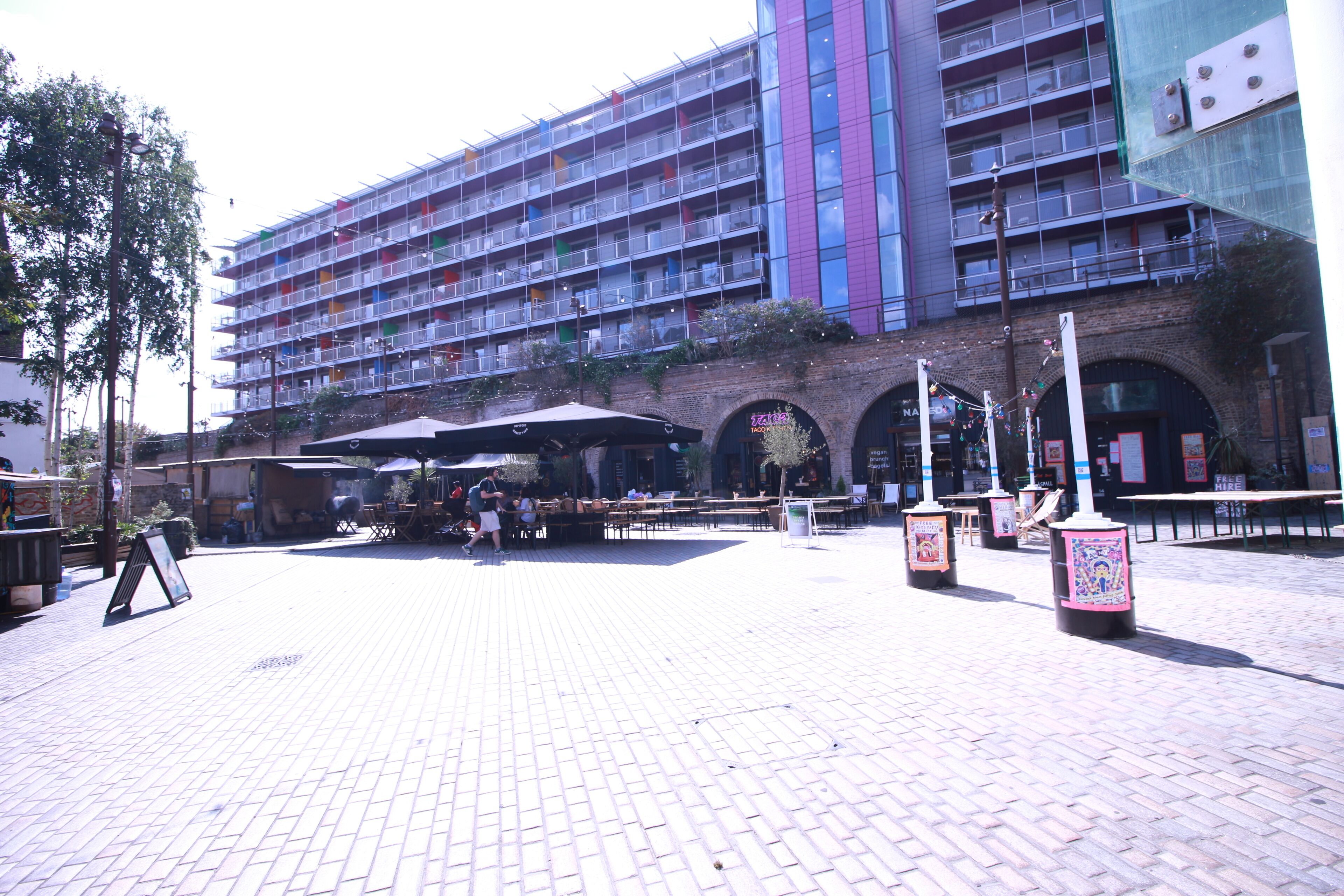 Ein mehrstöckiges Hotel mit Außenbereichen zum Sitzen und einem Innenhof mit Backsteinpflasterung.