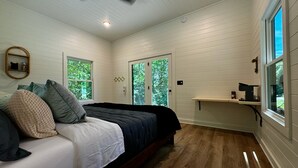 A bedroom with a bed, a ceiling fan, a window, and a door. - Mirror Cabin - Reflections (Balsam Grove)