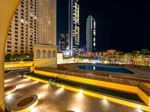 Hotellinäkymä yöllä: hotellissa on uima-allas, palmuja ja taustalla näkyy korkeita rakennuksia.