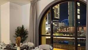 Mesa de jantar posta para quatro pessoas, com vista para a paisagem urbana à noite.