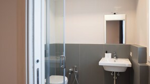 A modern bathroom with a toilet, a glass shower enclosure, and a sink with a mirror above it. - Bivio 281 suite&rooms (Carini)