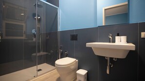 A modern bathroom with a glass shower enclosure, a white toilet, and a sink with a mirror above it. - Bivio 281 suite&rooms (Carini)