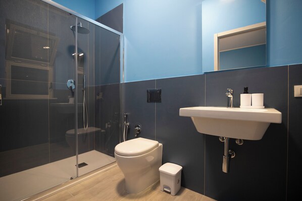 A modern bathroom with a glass shower enclosure, a white toilet, and a sink with a mirror above it.