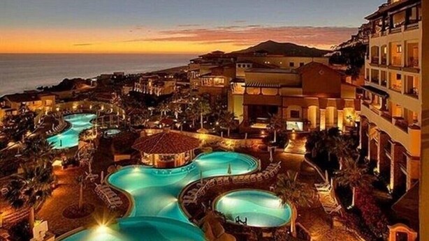 Un resort con múltiples piscinas, vistas a la playa y una variedad de edificios.