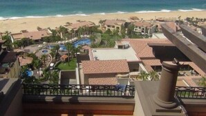 Un resort con vista a la playa, varias piscinas y una variedad de edificios con techos de tejas rojas.