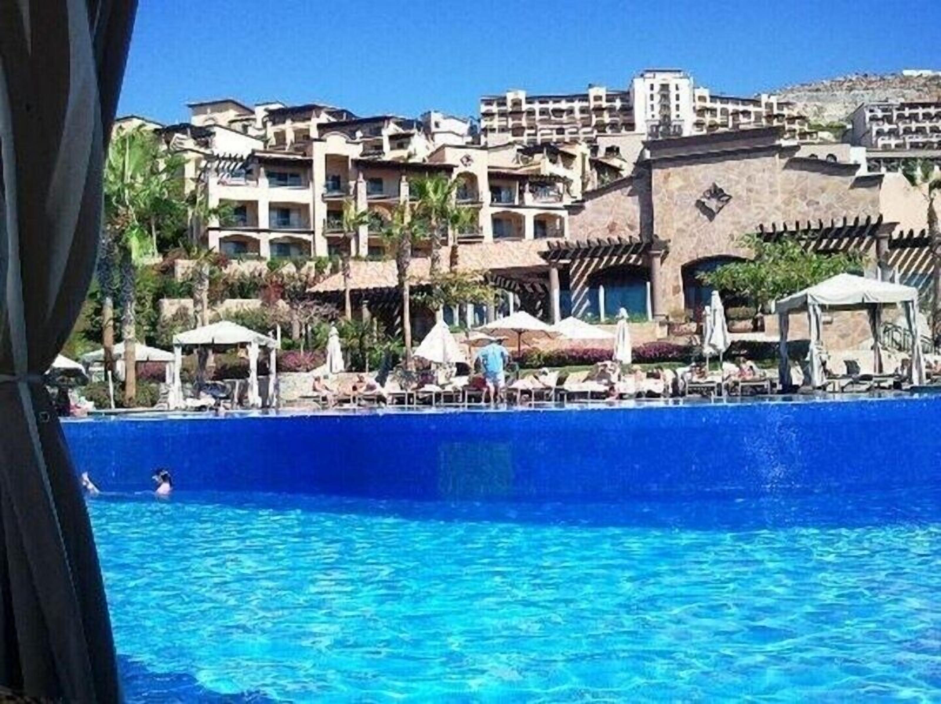 A resort with a swimming pool, multiple balconies, and outdoor umbrellas.