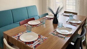 A dining area with a wooden table set for four, blue upholstered sofa, and decorative wall art. - Grandma pina mondello house (Palermo)