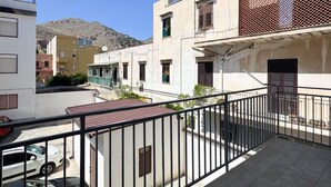 A balcony with a view of a residential street, a parked car, and a mountain in the background. - Grandma pina mondello house (Palermo)